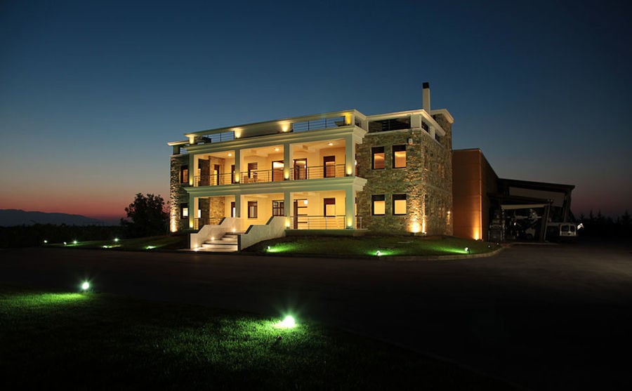 front view of 'Domaine Migas' illuminated building with two floors by night
